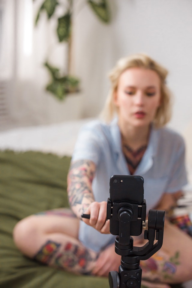 Uma mulher sentada gravando a si mesma com seu smartphone para um TikTok. 