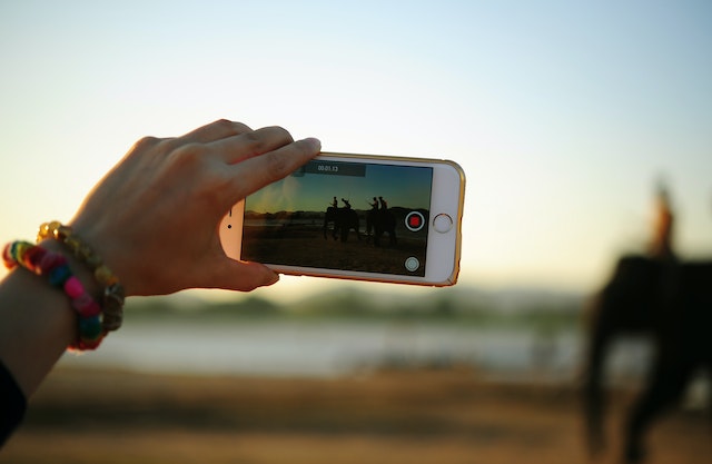 Unseen person recording video of people riding an elephant.