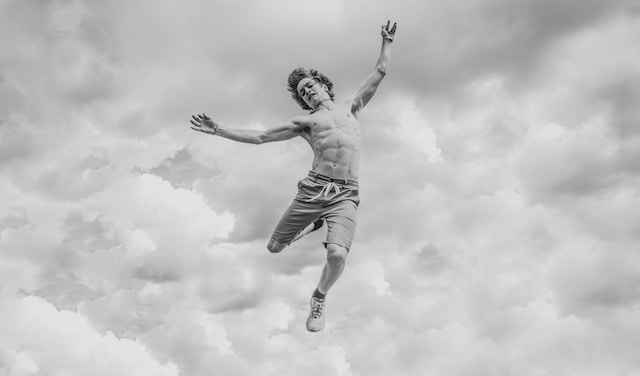 A man in the middle of a jump with clouds in the background. 