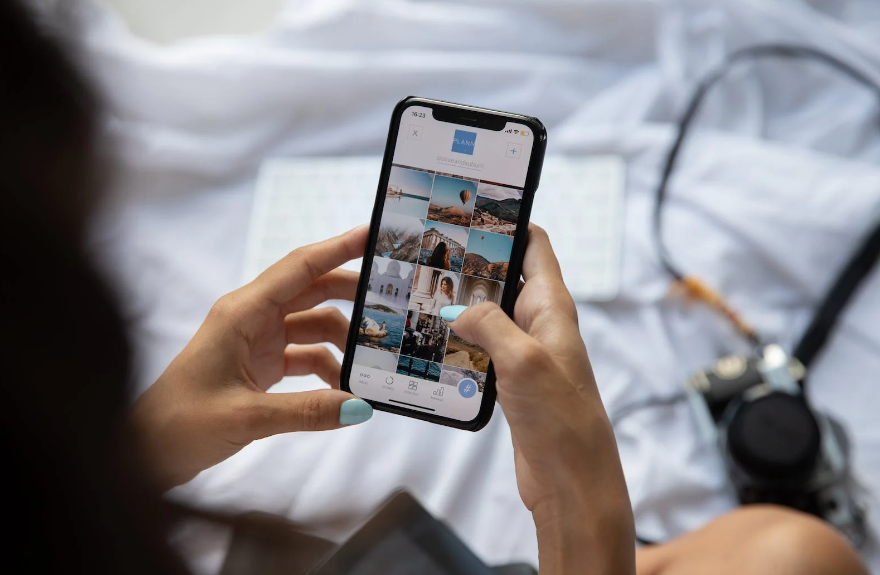 A woman sitting on her bed and using an app on the phone.