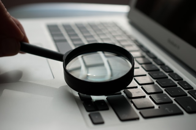 A magnifying glass on top of a laptop keyboard. 