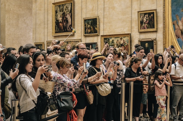 Dans un musée, un groupe de personnes est rassemblé autour d'une exposition et prend des photos. 