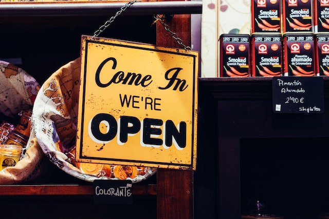 A yellow sign that says, “Come in, we’re open.”