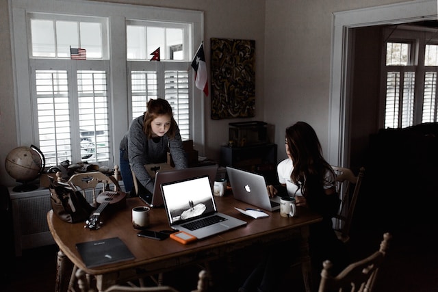 Duas mulheres trabalhando em seus laptops. 