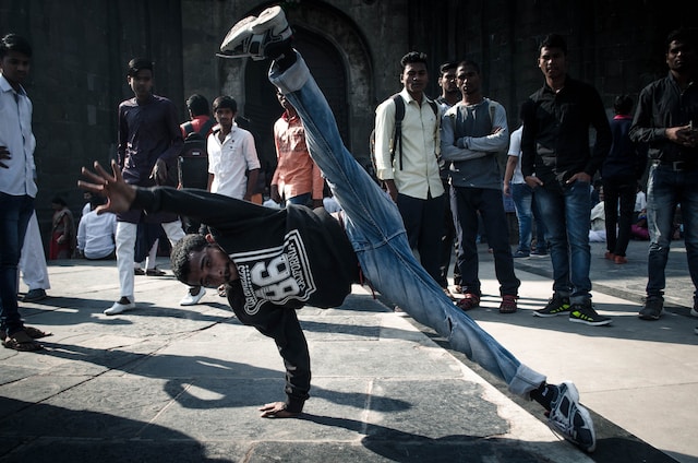 A man dancing outdoors and surrounded by people.