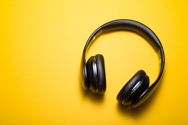 Black headphones on a yellow background. 