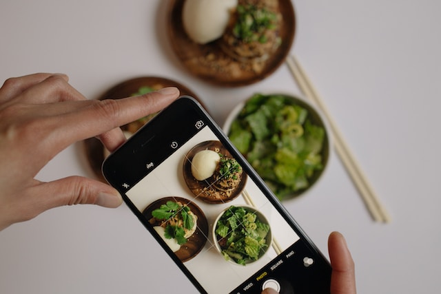 Iemand die foto's maakt van eten op tafel voor TikTok. 