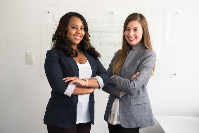 Two female professionals standing in front of a whiteboard. 