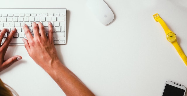 Una persona escribiendo comentarios en un teclado blanco. 