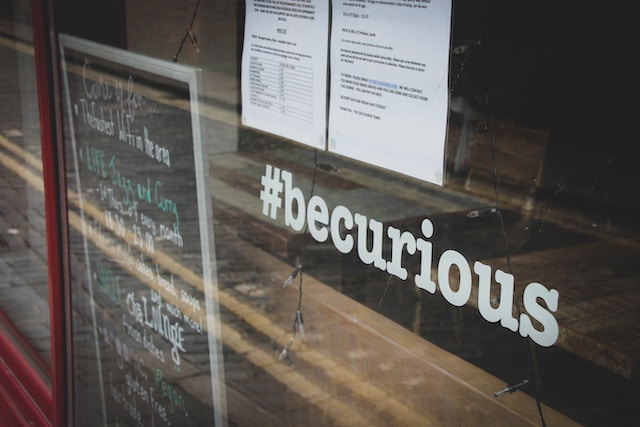 Panneau sur la vitrine d'un magasin indiquant "#becurious".