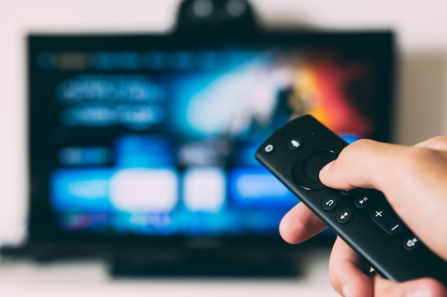 A person pressing buttons on a TV remote.