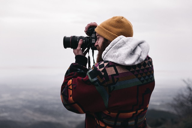 デジタル一眼レフカメラで写真を撮る山上の男。 