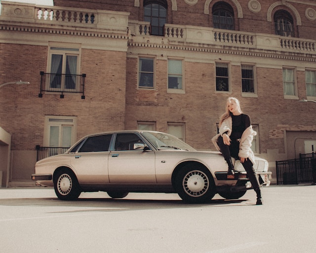 Un model feminin care stă pe capota unei mașini. 