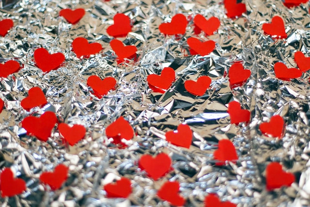 Tiny, red heart cut-outs on silver foil. 