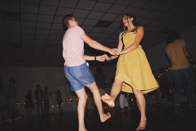 A man in blue shorts dancing with a woman in a yellow dress.