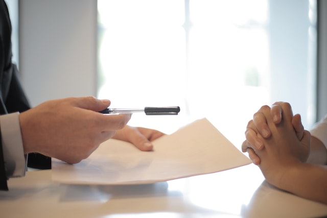 Un empresario entrega a un cliente un documento para que lo firme.