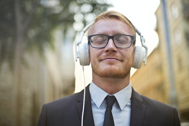 Un bărbat ascultă fericit un cântec cu căștile pe urechi.