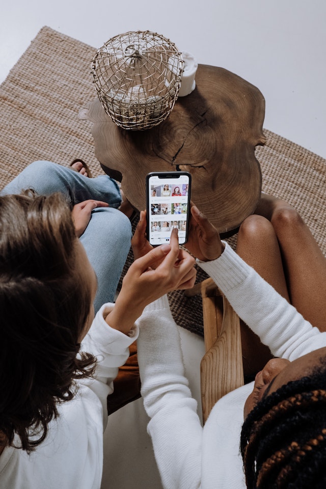 Two girls scrolling through TikTok on a smartphone. 