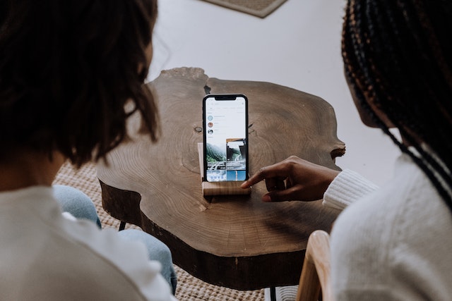 Two girls looking at a smartphone viewing the TikTok app.