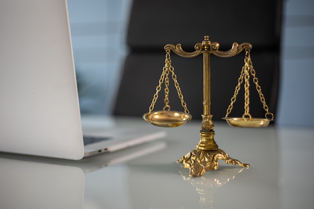 A golden balance scale and a laptop on an office table.