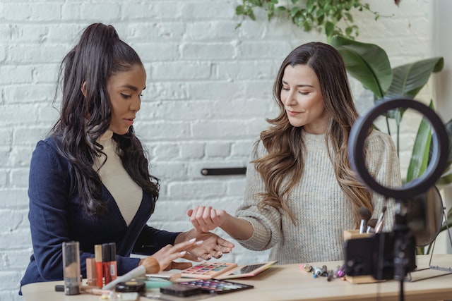 Two women recording a makeup tutorial together for TikTok.