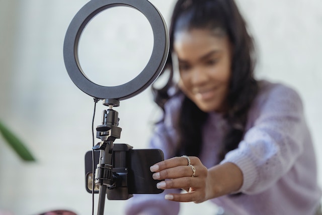 Uma garota com um suéter cinza gravando um vídeo para o TikTok.