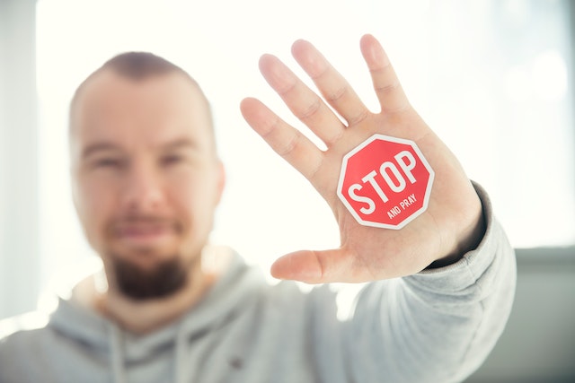 Nahaufnahme der Hand eines Mannes mit dem Stoppschild-Aufkleber.