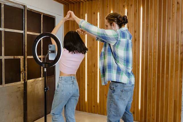Um homem e uma mulher criando um vídeo dançando na frente da câmera de um smartphone. 