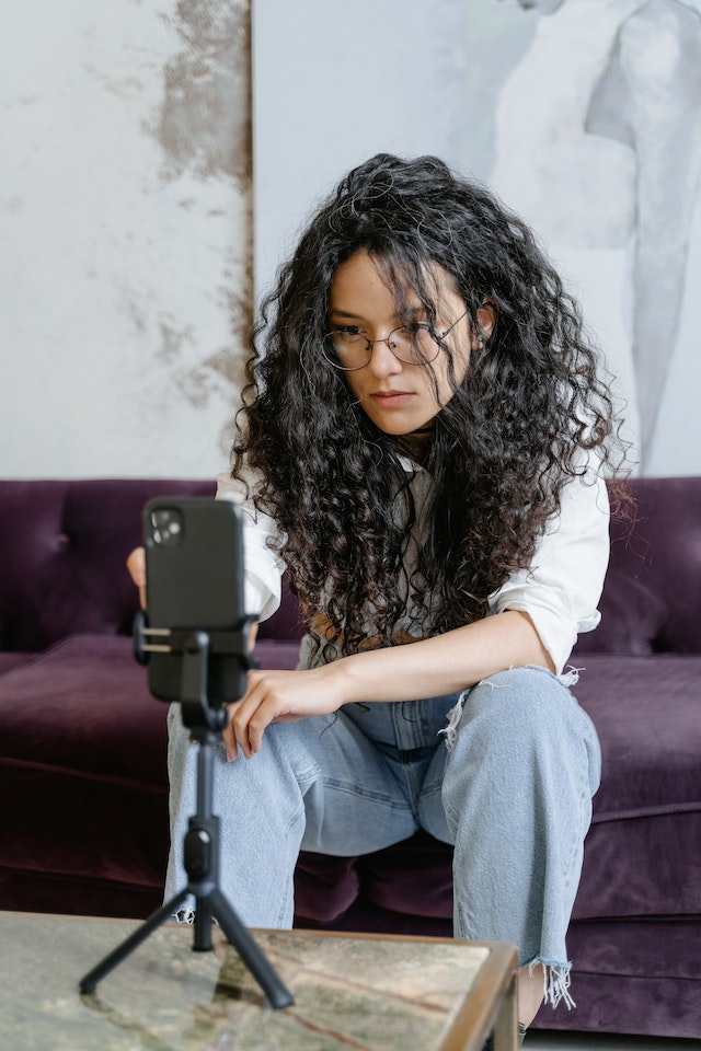 A girl sitting and recording a video for TikTok from her smartphone.