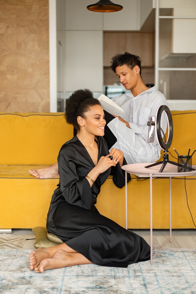 Une fille assise à côté d'un homme enregistre un tutoriel de maquillage pour TikTok. 