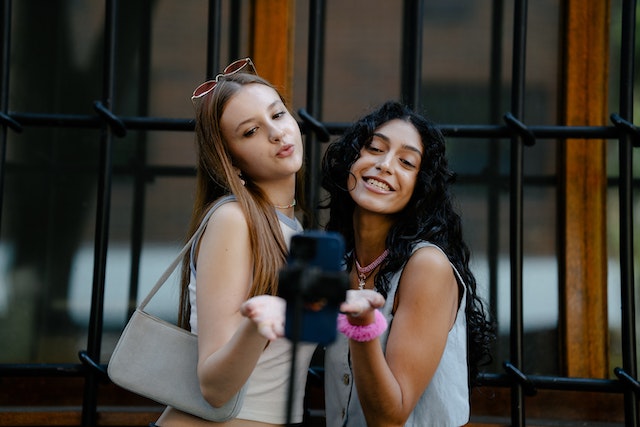 Twee lachende jongedames maken een foto met een smartphone.  
