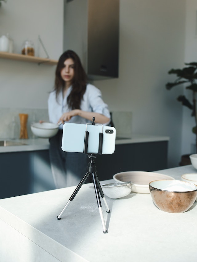 A girl making a TikTok while cooking.