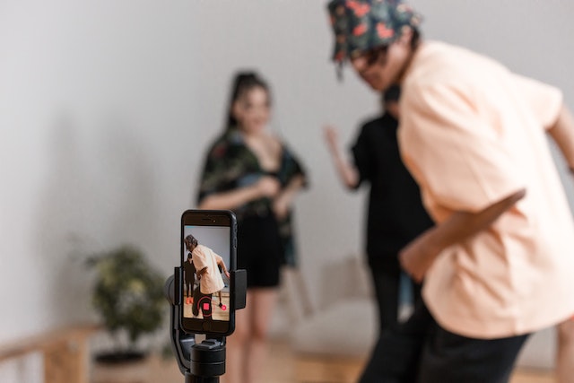 スマートフォンの前で踊りながらTikTok用の動画を撮影する男性。