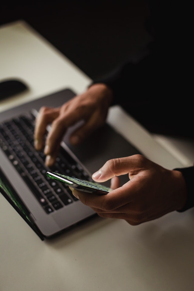 Iemand die tegelijkertijd een laptop en een smartphone gebruikt. 