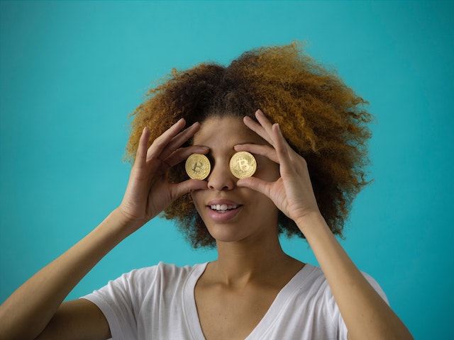 A woman holding and covering her eyes with two gold coins.