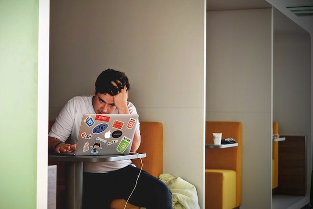 一个沮丧的男人坐在电脑前发呆。