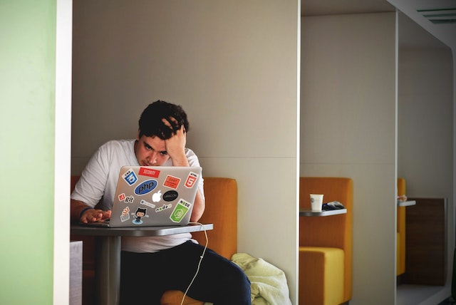 Un homme frustré, assis et fixant son PC.