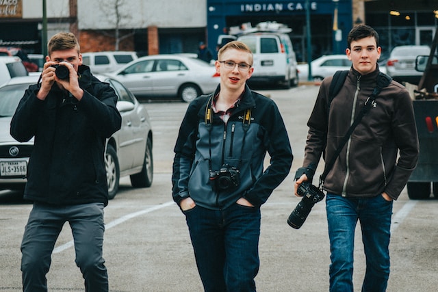 Three men carrying DSLR cameras.