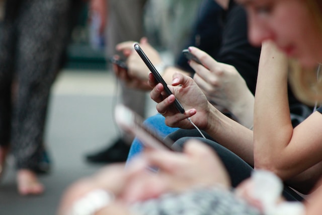 Un gruppo di persone che guardano video sui loro smartphone. 