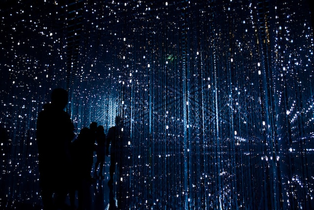 Siluetas de personas en una habitación oscura llena de luces. 