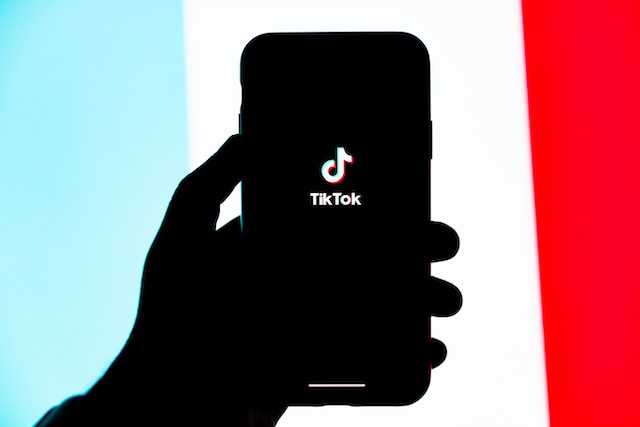 Uma pessoa segurando um telefone celular com o ícone do TikTok na tela. 