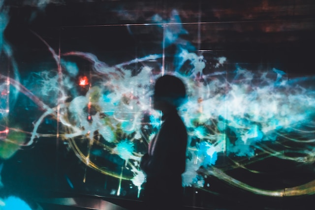 A person’s dark profile in front of colorful lights.