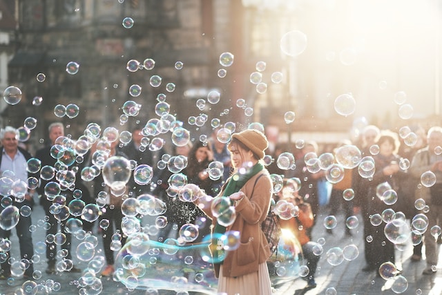 A woman standing outside with bubbles surrounding her.