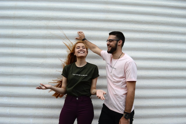 Um rapaz e uma moça de pé e sorrindo.