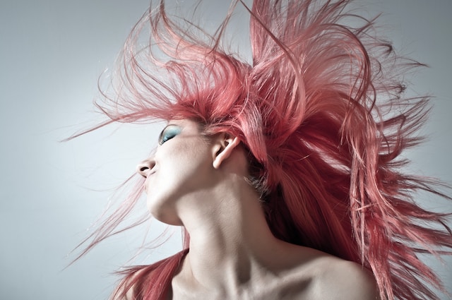 A woman whipping her long, pink hair.