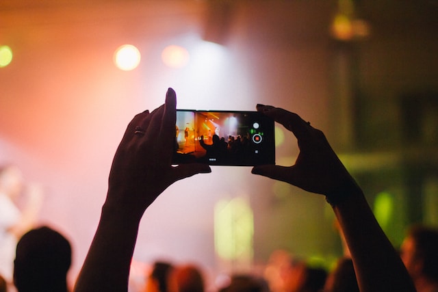 Een close-up van een persoon die de video opneemt van een populaire TikTok influencer tijdens een live show.