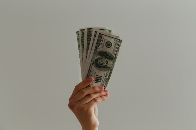 A hand holding 100-dollar bills.