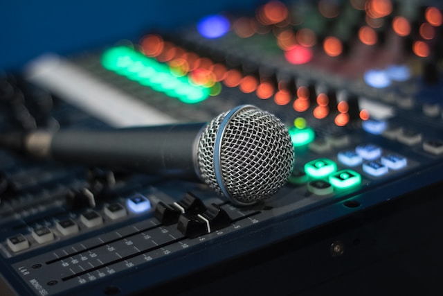 A microphone on top of an analog audio mixer.