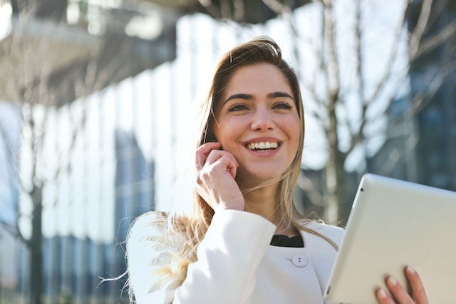 Uma mulher sorridente segurando um tablet branco.