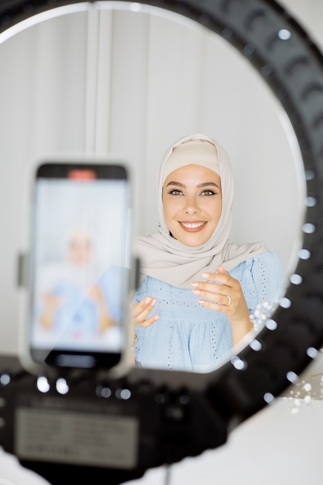 A girl in a Hijab recording a video for TikTok.